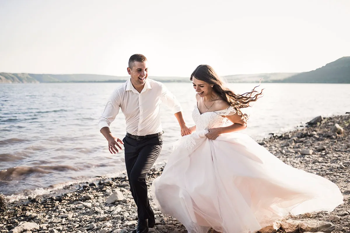 Bride and groom laughing run together against rays 2022 02 14 21 39 48 utc
